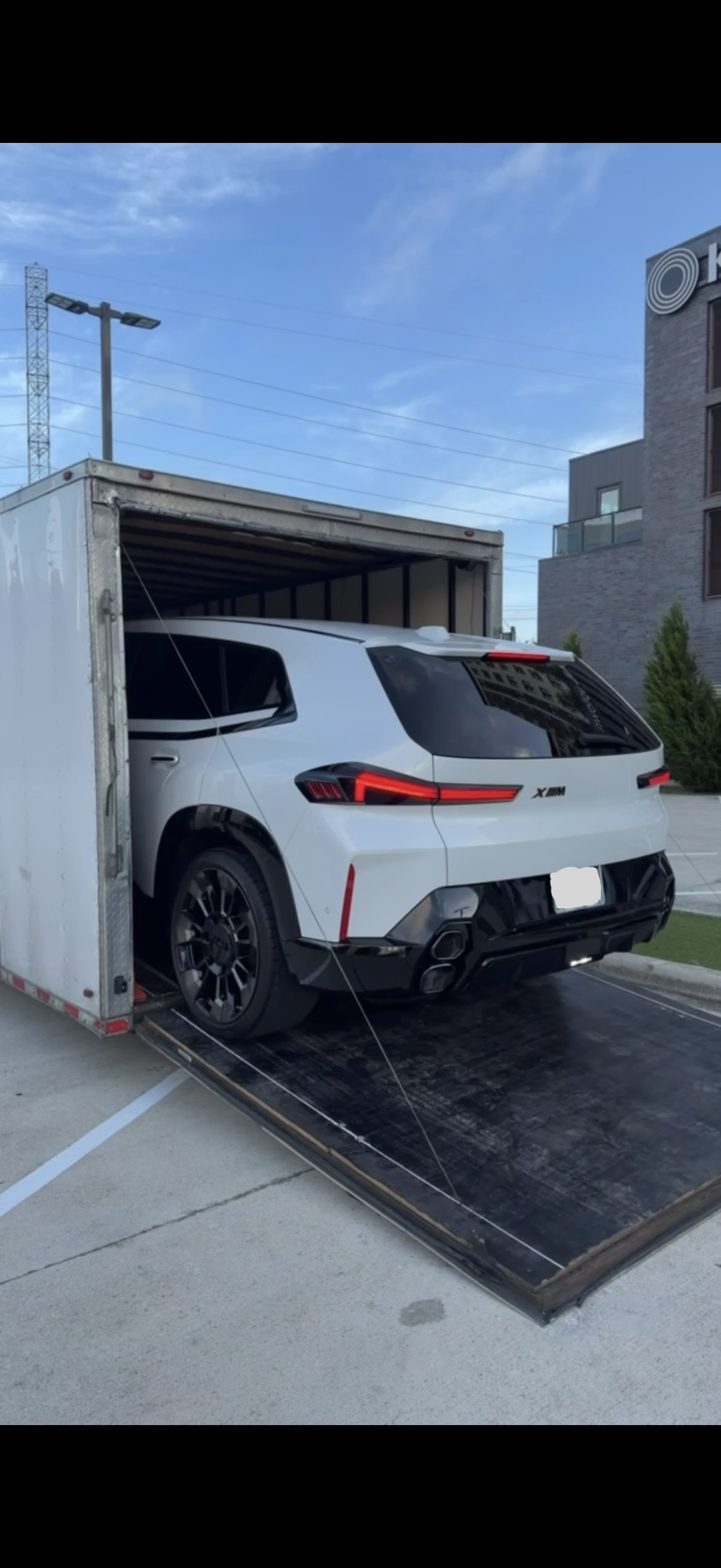White BMW X5 being loaded into an enclosed transport trailer
