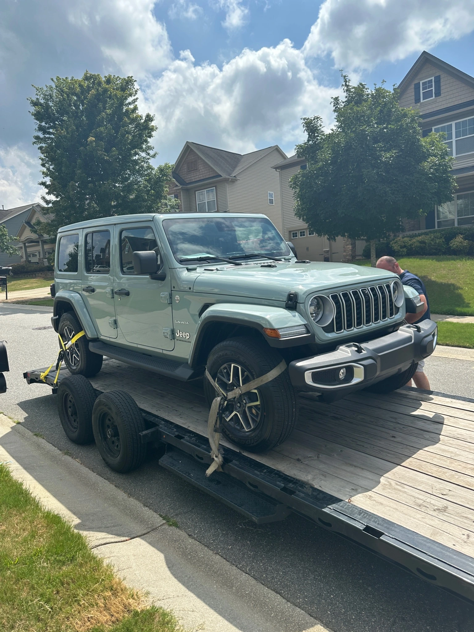 Green Jeep Wrangler secured on a trailer for delivery